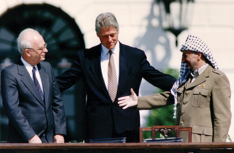  PLO CHAIRMAN Yasser Arafat reaches to shake hands with prime minister Yitzhak Rabin, as US president Bill Clinton stands between them, after the signing of the Israeli-PLO peace accord, at the White House in Washington, on September 13, 1993. (photo credit: GARY HERSHORN/REUTERS)