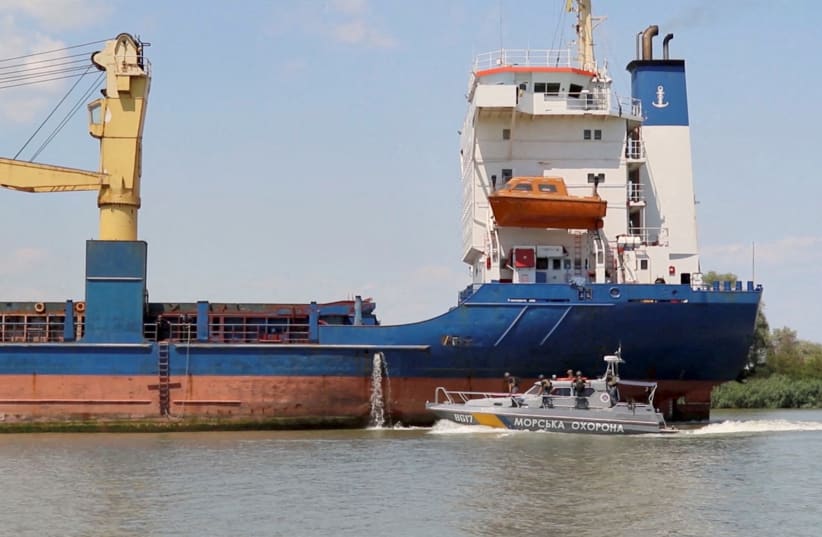   A Cargo ship sails followed by a Ukraine’s Coast Guard cutter through Bystre rivermouth, which connects the Black Sea and Danube, at a location given as Izmail district of Odesa region, Ukraine in this screen grab obtained from a handout video released on July 15, 2022 (photo credit: OPERATIONAL COMMAND SOUTH PRESS SERVICE/HANDOUT VIA REUTERS)