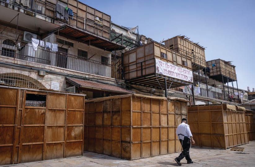  A MAN walks past a row of ‘sukkot,’ temporary dwellings, already built ahead of the holiday, on a street in the Mea She’arim neighborhood, in Jerusalem, last week. (photo credit: Chaim Goldberg/Flash90)