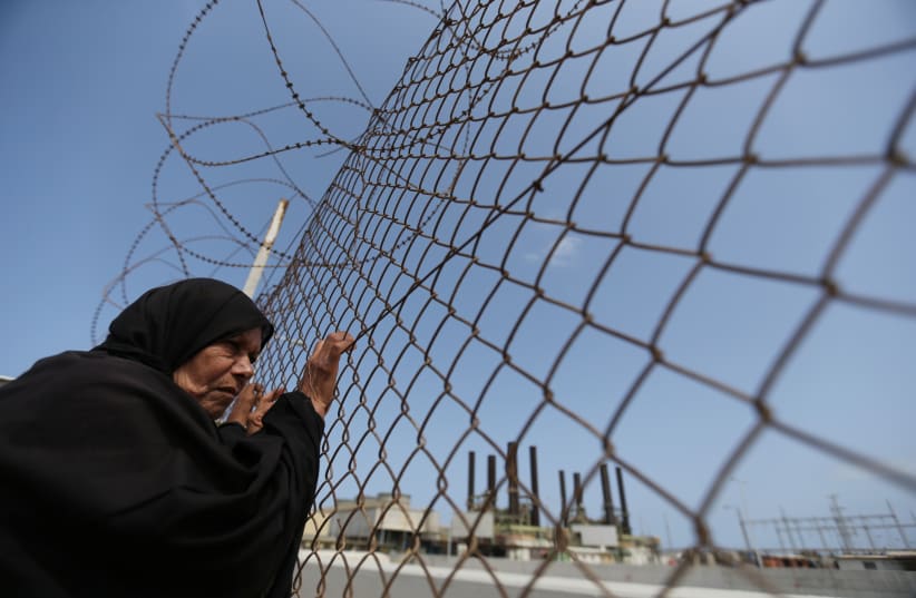  A Palestinian woman stands by a fence during a protest calling for an end to the power crisis, outside the power plant in the central Gaza Strip April 23, 2017. (photo credit: REUTERS/IBRAHEEM ABU MUSTAFA)