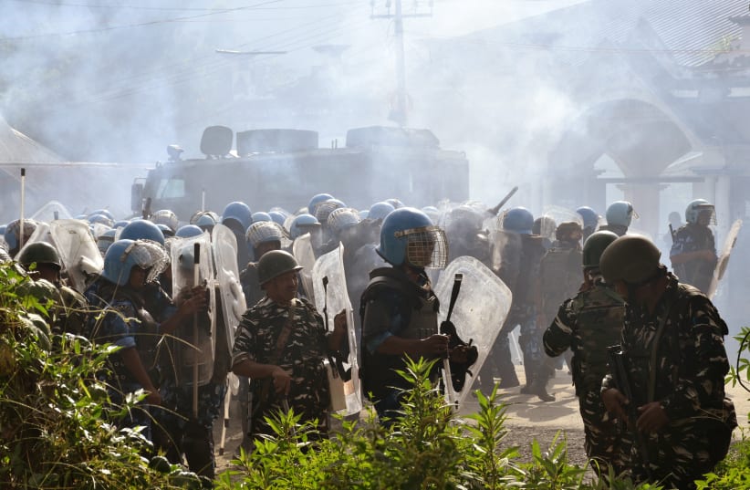  Police officers stand amidst smoke billowing out from tear gas shells fired to disperse the crowd gathered to demand the removal of the army barricades in Bishnupur district, in the northeastern state of Manipur, India, September 6, 2023 (photo credit: REUTERS/STRINGER)