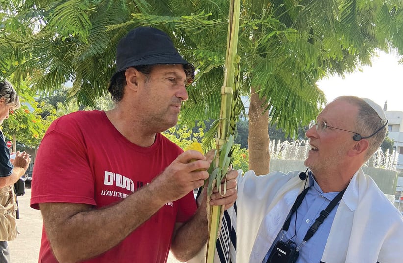  A MAN wearing a shirt with a slogan in support of women’s rights is given the Sukkot Four Species by the writer at yesterday’s prayer service at Dizengoff Square (photo credit: RACHEL SHARON)