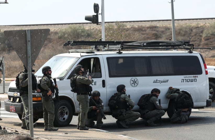 Israeli border police take cover by a vehicle following a mass infiltration by Hamas by Hamas terrorists from the Gaza Strip, near Sderot in southern Israel October 8, 2023 (photo credit: RONEN ZVULUN/REUTERS)