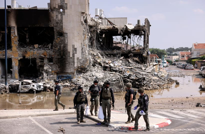 Israeli security gather near a rifle at the site of a battle following a mass infiltration by Hamas terrorists from the Gaza Strip, in Sderot, southern Israel October 8, 2023 (photo credit: RONEN ZVULUN/REUTERS)
