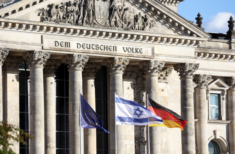  An Israeli flag flutters next to a German and a EU flag, one day after Hamas' attacks on Israel, outside the Reichstag building in Berlin, Germany, October 8, 2023. (photo credit: REUTERS/Liesa Johannssen)