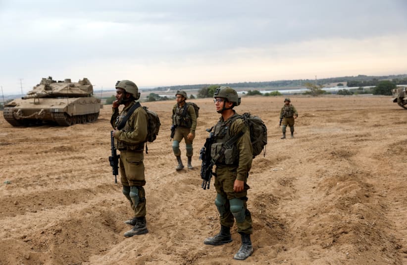  Israeli soldiers look on in an area where Israeli tanks and militiary vehicles amass at the Israeli side of the Gaza border, as violence around the nearby Gaza Strip mounts following a mass-rampage by armed Palestinian infiltrators, October 9, 2023. (photo credit: REUTERS/AMIR COHEN)