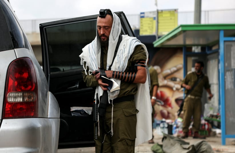  An Israeli soldier wears a Jewish prayer shawl and tefillin as he prays, in Ashkelon, southern Israel October 10, 2023. (photo credit: REUTERS/VIOLETA SANTOS MOURA)
