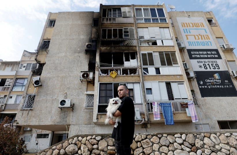 A man holds his dog after a rocket, launched from the Gaza Strip, landed in Ashkelon, southern Israel, October 11, 2023. (photo credit: AMIR COHEN/REUTERS)