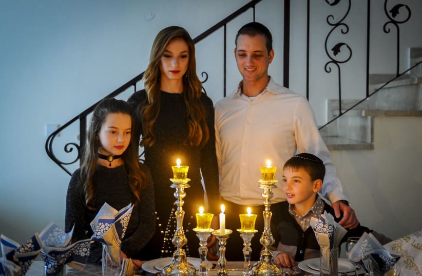A FAMILY gathers around the Shabbat candles (photo credit: MENDY HECHTMAN/FLASH90)