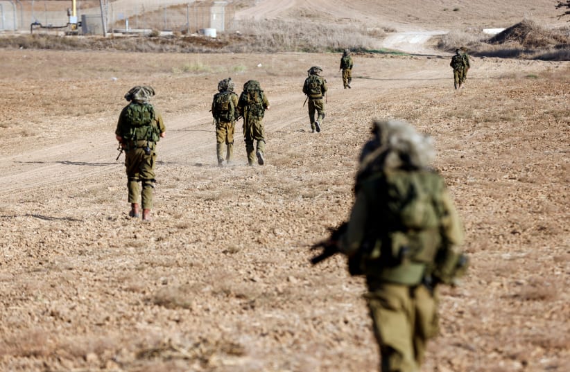  Israeli soldiers walk on grassy terrain near Israel's border with Gaza in southern Israel, October 12, 2023. (photo credit: REUTERS/AMIR COHEN)