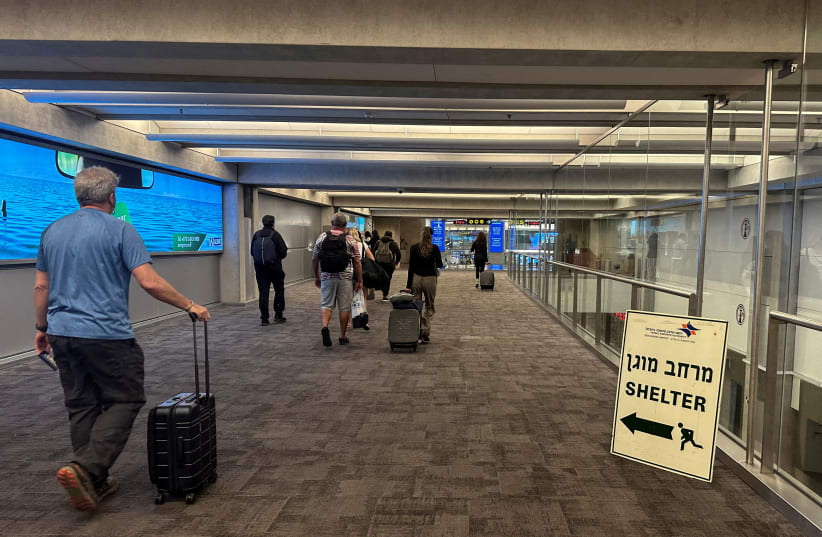  People walk next to a sign directing for Shelter after landing in Israel at the arrivals section of Ben Gurion International airport in Lod near Tel Aviv, Israel October 11, 2023 (photo credit: REUTERS/MARIUS BOSCH)