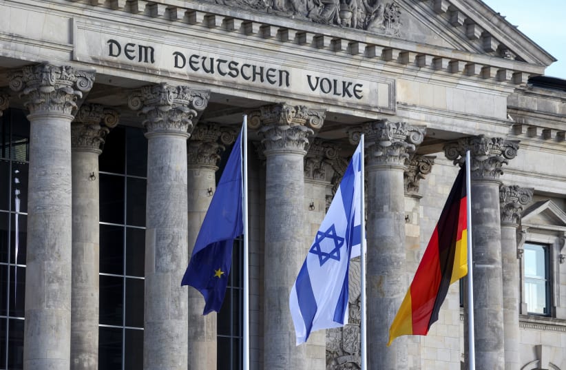  An Israeli flag flutters next to a German and a EU flag, one day after Hamas' attacks on Israel, outside the Reichstag building in Berlin, Germany, October 8, 2023.  (photo credit: REUTERS/Liesa Johannssen)