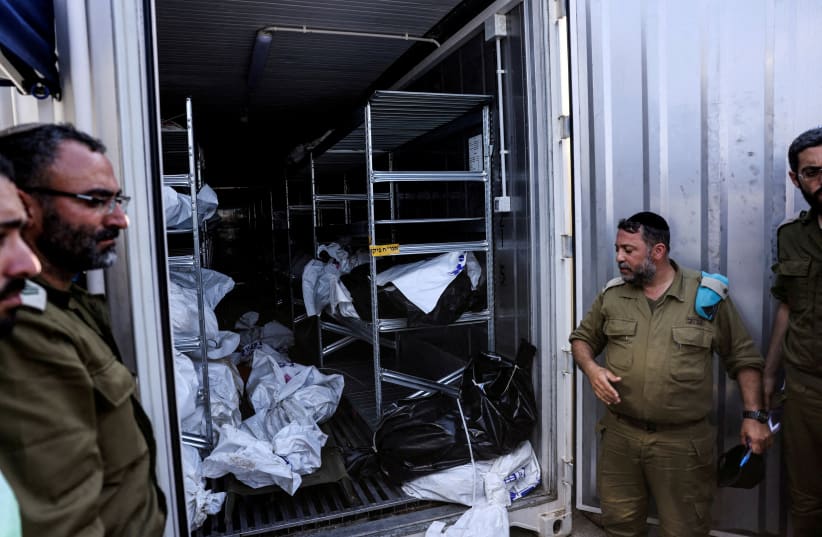  Israeli military officers stand by a container in which bodies of the dead are stored before their relatives are called to identify them, following a mass infiltration by Hamas terrorists from the Gaza Strip, in Ramla, Israel, October 13, 2023 (photo credit: REUTERS/Ronen Zvulun)