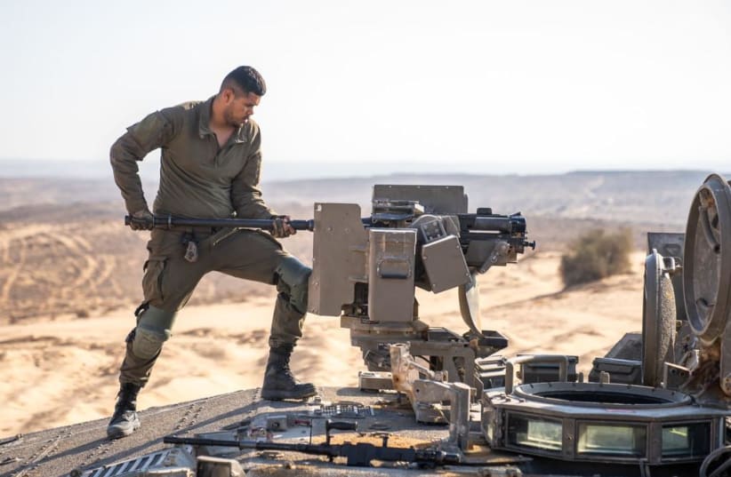  An IDF soldier works on a tank mounted machine gun ahead of the expansion of the offensive against Hamas. October 14, 2023. (photo credit: IDF)