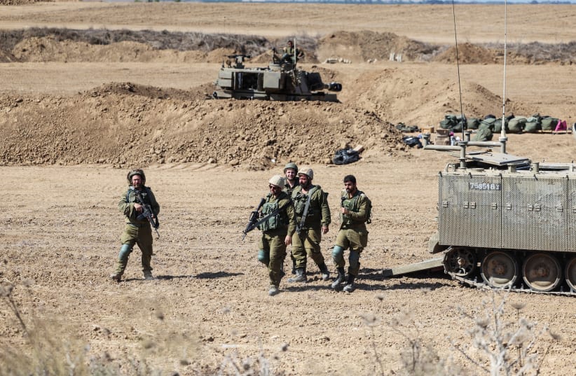  Israeli soldiers walk next to an Armoured Personnel Carrier (APC) near Israel's border with the Gaza Strip, in southern Israel October 15, 2023. (photo credit: REUTERS/Ronen Zvulun)