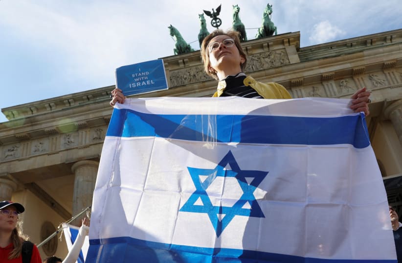  AT THE Brandenburg Gate, in Berlin, last week, an Israel supporter holds the Israeli flag and a sign that reads ‘I stand with Israel.’  (photo credit: REUTERS/Liesa Johannssen)