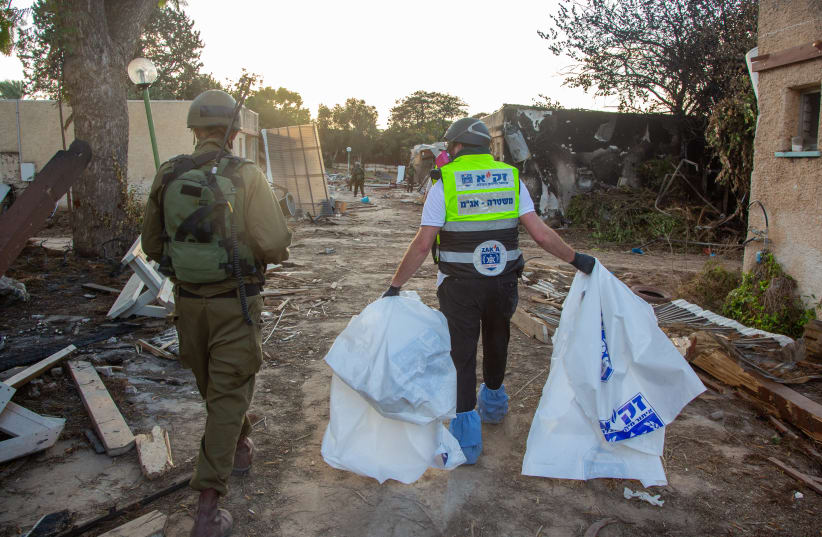  Members of Zaka walk through the destruction caused by Hamas Militants in Kibbutz Kfar Aza, as they collect the dead bodies, near the Israeli-Gaza border, in southern Israel, October 15, 2023.  (photo credit: EDI ISRAEL/FLASH90)