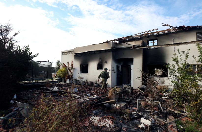  An Israeli soldier walks towards the remains of a burnt house, following a deadly infiltration by Hamas terroirsts from the Gaza Strip, in Kibbutz Beeri in southern Israel October 17, 2023 (photo credit: REUTERS/Ronen Zvulun)