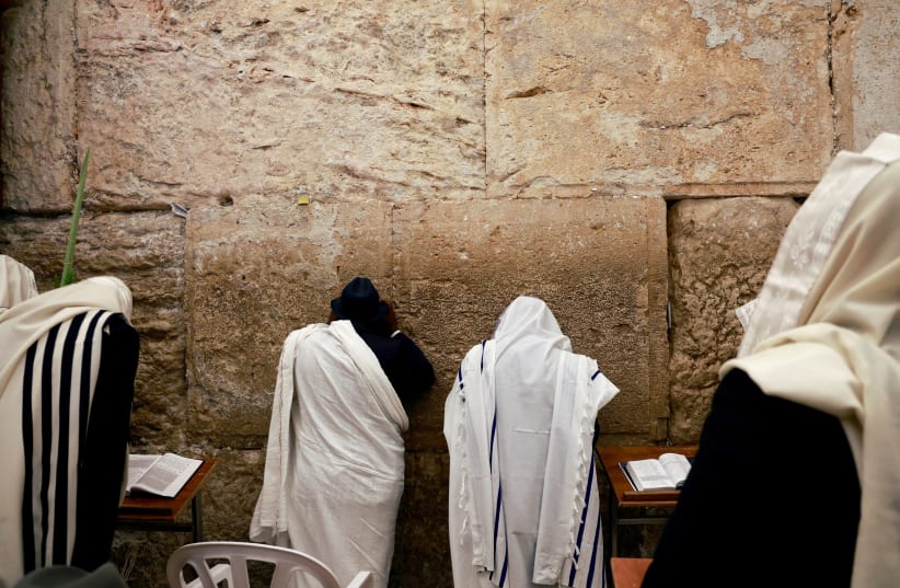  Worshippers wearing prayer shawls take part in the priestly blessing during the Jewish holiday of Sukkot at the Western Wall, Judaism's holiest prayer site, in Jerusalem's Old City, October 2, 2023 (photo credit: REUTERS/AMMAR AWAD)