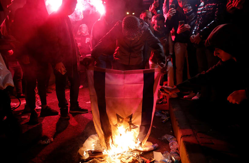  Pro-Palestinian demonstrators set an Israeli flag on fire during a protest near the Israeli Consulate as the conflict between Israel and Hamas continues, in Istanbul, Turkey October 18, 2023 (photo credit: REUTERS/DILARA SENKAYA)