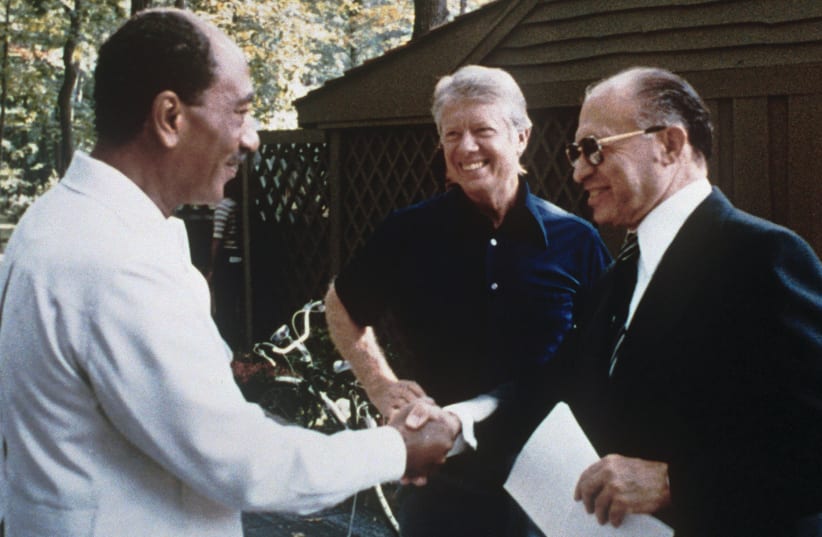  PM MENACHEM BEGIN (R) and Egyptian president Anwar Sadat shake hands in the presence of a beaming US president Jimmy Carter at Camp David, Maryland, 1978. The peace treaty was signed March 26, 1979, and went into effect in January 1980.  (photo credit: Wikimedia Commons)
