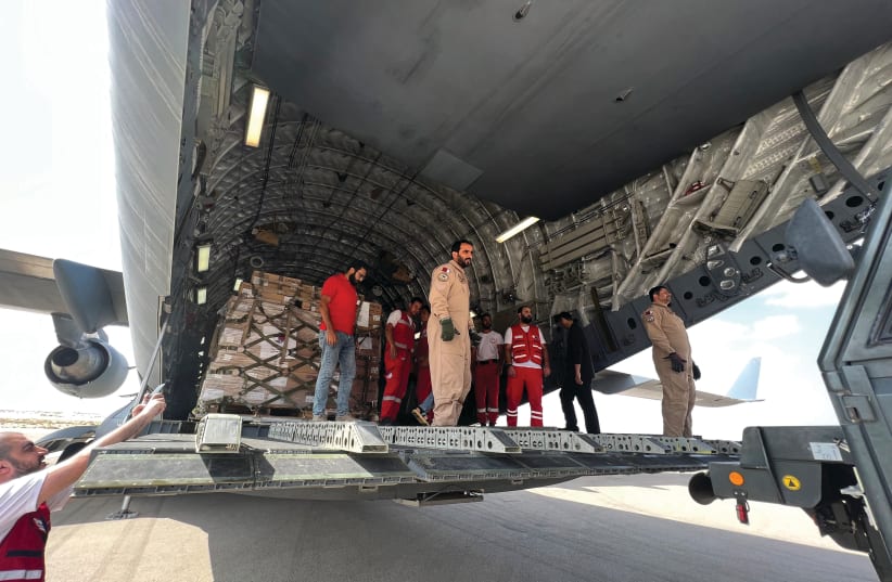 VOLUNTEERS FROM Qatar and Egypt’s Red Crescent unload aid destined for the Gaza Strip, at Egypt’s el-Arish airport in the northern Sinai this week. (photo credit: Callum Paton/AFP via Getty Images)