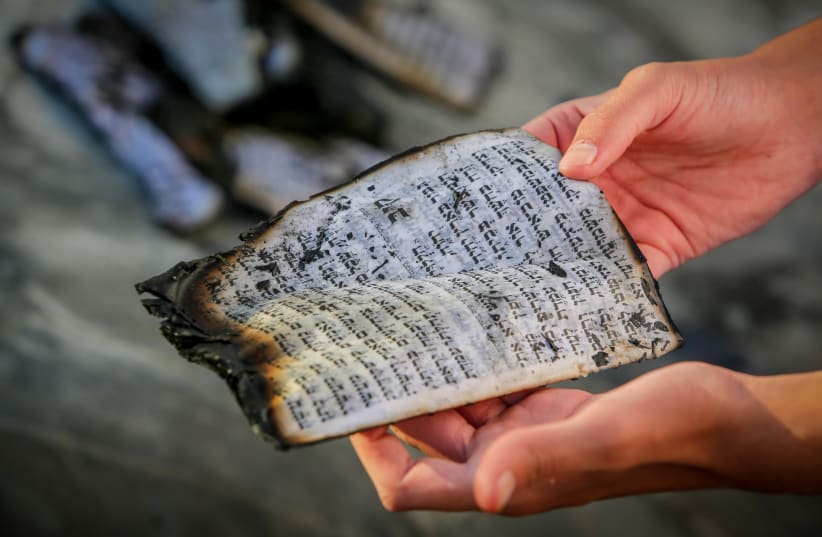  A SCORCHED page from the Book of Psalms is recovered in a home in Ashkelon hit by a rocket from the Gaza Strip, on October 7. (photo credit: EDI ISRAEL/FLASH90)
