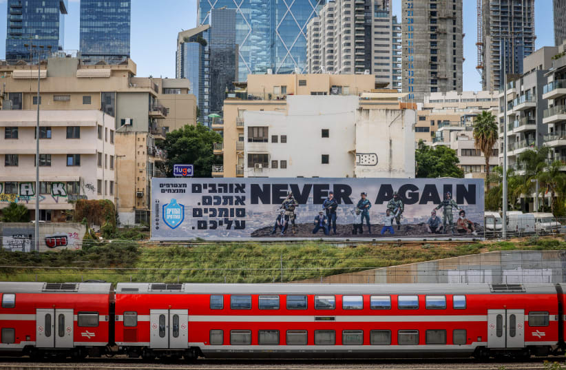  A large billboard with the words "Never Again" above the Ayalon highway in Tel Aviv, October 18, 2023. (photo credit: Chaim Goldberg/Flash90)