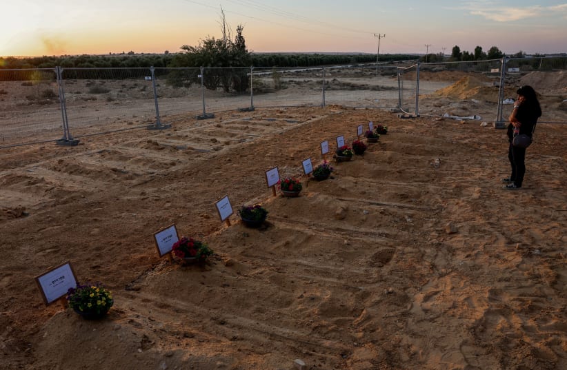  A woman looks at newly dug graves for the victims of the October 7th attack during the funeral of Albert Miles, 80, who was killed in his home in Kibbutz Beeri in the deadly infiltration of Israel by Hamas gunmen from the Gaza Strip, at the cemetery in Kibbutz Revivim, in southern Israel, October 3 (photo credit: REUTERS/EVELYN HOCKSTEIN)