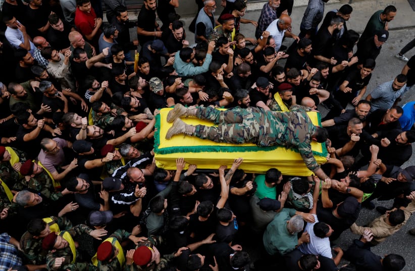  Nazih, son of Hezbollah member Mounir Youssef Achour, who was killed in southern Lebanon amidst tension between Israel and Hezbollah, lies on top of his father's coffin as he mourns him during his funeral, in Chaqra Lebanon, October 30, 2023. (photo credit: REUTERS/ZOHRA BENSEMRA)