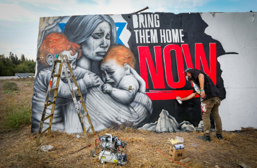 An artist sprays a graffiti for the release of  Israelis held hostage by Hamas terrorists in Gaza, in the Jezreel Valley, on October 30, 2023 (photo credit:  Anat Hermony/Flash90)