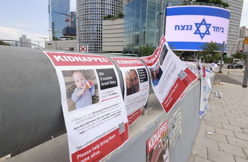  AN ISRAELI flag displaying the ubiquitous slogan ‘Together we will win’ is seen in Tel Aviv close to a display of posters calling for the release of the captives abducted by Hamas. (photo credit: MARC ISRAEL SELLEM/THE JERUSALEM POST)