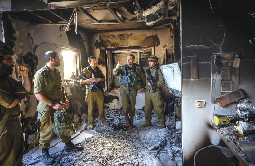  Israeli soldiers stand amid the destruction at Kibbutz Be'eri. The State of Israel bowed its head and mourned, but it also rose from the carnage to fight back, says the writer. (photo credit: YONATAN SINDEL/FLASH90)