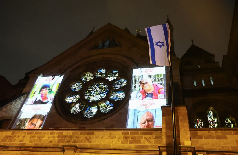  Pictures of people kidnapped during the October 7 attack on Israel by Palestinian Islamist group Hamas are projected on a synagogue, during a silent march from Cologne Cathedral to a synagogue to mark the eve of the commemoration of Kristallnacht, also known as the Night of Broken Glass, 85 years a (photo credit: REUTERS/WOLFGANG RATTAY)