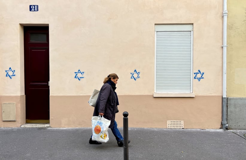  A woman walks past a building tagged with Stars of David in Paris, France, October 31, 2023 (photo credit: REUTERS/LUCIEN LIBERT)