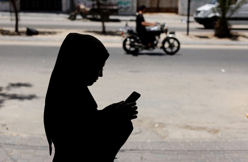  A Palestinian woman uses a Phone app that allows Gaza women to report domestic abuse anonymously, outside Gaza Women's Center in Gaza City May 31, 2022 (photo credit: REUTERS/MOHAMMED SALEM)