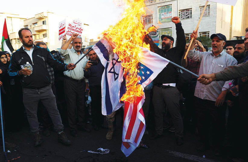  IRANIAN DEMONSTRATORS burn US and Israeli flags during a protest in Tehran on October 18.  (photo credit: Majid Asgaripour/WANA/via Reuters)