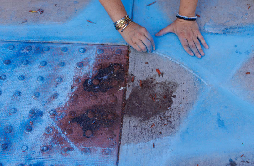 Chalk drawer Elena Colombo of the Hamakom Synagogue draws a blue star around blood at the exact location on the sidewalk of the alleged assault on Paul Kessler on Sunday in Thousand Oaks, California, U.S., November 7, 2023. (photo credit: MIKE BLAKE/REUTERS)