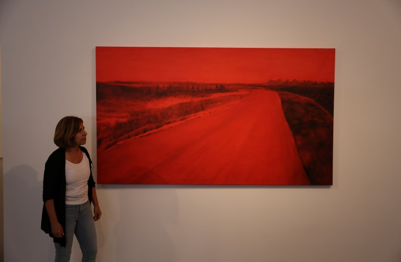  Ziva Jelin, an Israeli artist from Kibbutz Beeri in Israel's south stands next to her painting "Curving Road", which depicts a scene of the road leading to her kibbutz which neighbours the Gaza Strip, after it was exhibited at the Israel Museum in Jerusalem November 12, 2023. (photo credit: REUTERS/Ronen Zvulun)