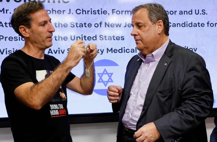  Ruby Chen, the American father of a hostage held by Hamas shows a dog tag with the words "Bring them home" on it to the former New Jersey Governor Chris Christie, at Sourasky Medical Center (Ichilov) in Tel Aviv, Israel November 12, 2023 (photo credit: REUTERS/AMIR COHEN)