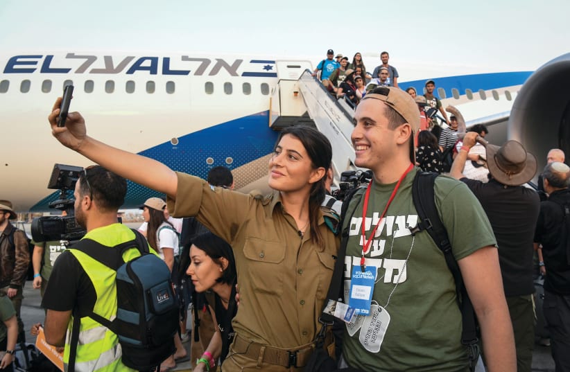  An IDF soldier takes a selfie at Ben-Gurion Airport with a new immigrant who intends to serve in the Israeli military, arriving on a flight with other North American olim, organized by the Nefesh b'Nefesh organization, 2019. (photo credit: FLASH90)