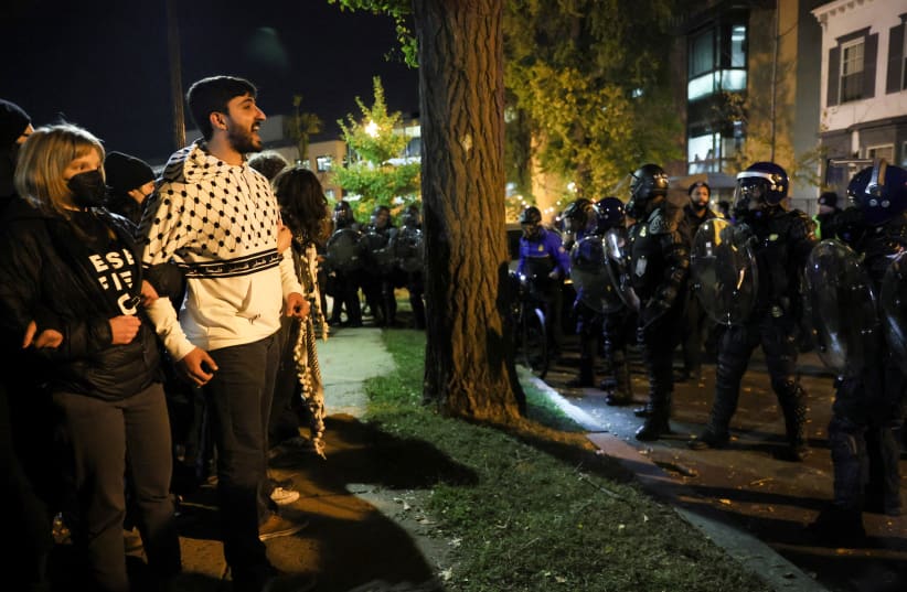  Demonstrators stand facing police officers as people march during a multi-denominational event hosted by the Democratic Socialists of America, IfNotNow Movement and Jewish Voice for Peace calling for a ceasefire in the conflict between Israel and Palestinian Islamist group Hamas, in Washington, DC. (photo credit: LEAH MILLIS/REUTERS)