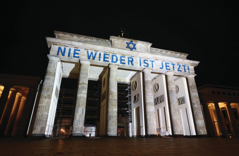  BERLIN’S BRANDENBURG Gate is illuminated with the Star of David and the blue of the Israeli flag, last week. The displayed message reads ‘Never again is now!’  (photo credit: Lisi Niesner/Reuters)