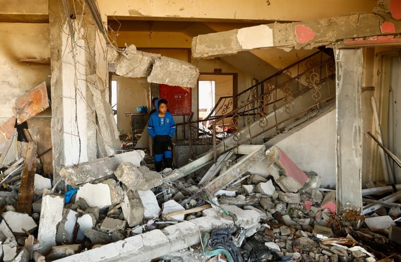  A boy walks among debris at the site of an Israeli strike on the apartment building, amid the ongoing conflict between Israel and Palestinian Islamist group Hamas, in Khan Younis in the southern Gaza Strip November 18, 2023 (photo credit: REUTERS/IBRAHEEM ABU MUSTAFA)