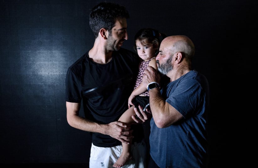  Rami Gold, his son Ran and granddaughter Hali, survivors of a deadly infiltration by Hamas gunmen on Kibbutz Beeri (photo credit: REUTERS/Ronen Zvulun)