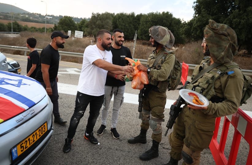  Druze residents hand out food to Israeli soldiers who guard on a road near the Israeli border with Lebanon, on October 9, 2023.  (photo credit: DAVID COHEN/FLASH 90)