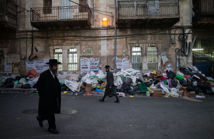  Ultra Orthodox Jews walk next to a pile of garbage in Jerusalem's Mea Shearim neighbourhood on January 5, 2016 (photo credit: YONATAN SINDEL/FLASH90)