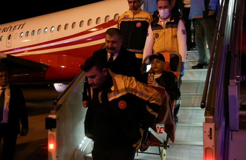 Turkish Health Minister Fahrettin Koca walks as medical staff carry a Palestinian cancer patient who was evacuated from Gaza to Egypt and brought to Turkey by plane, at Esenboga Airport in Ankara, Turkey November 16, 2023 (photo credit: REUTERS/Cagla Gurdogan/File Photo)