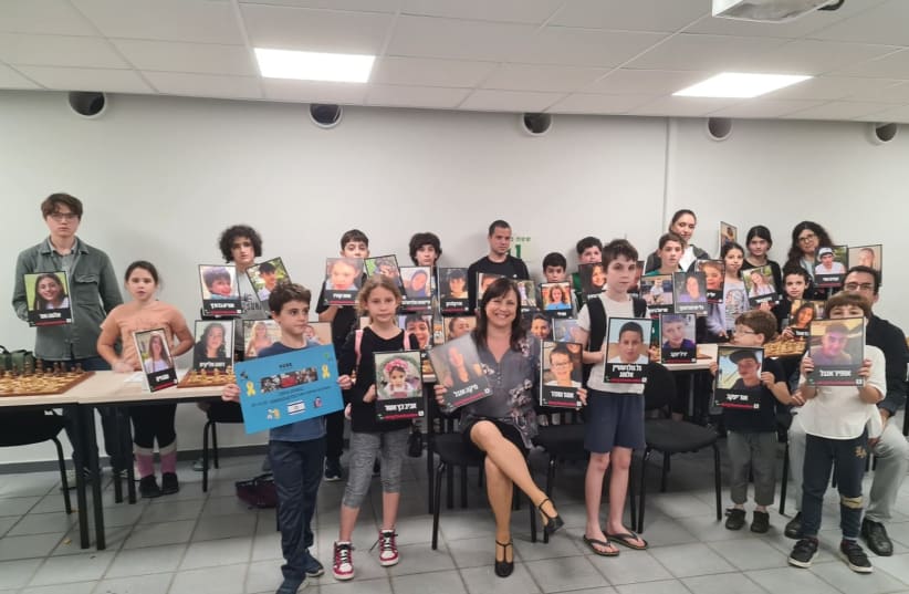  Sofia Polgar and the participants in "Chess for Solidarity" competition hold up the faces of abducted children. (photo credit: SAVYON CITY SPOKESPERSON)