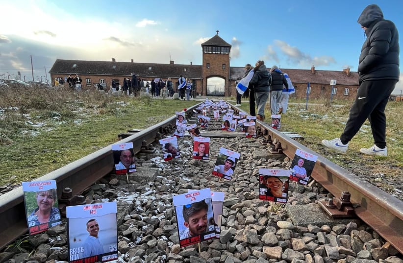  British students on a trip to Poland placed pictures of the nearly 200 Israeli hostages still in Hamas captivity on the train tracks leading up to the Auschwitz-Berkenau death camp, on November 26, 2023. (photo credit: JROOTS)